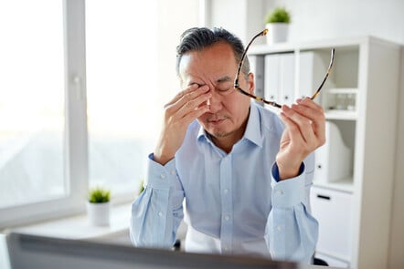 Tired IT worker rubs his eyes